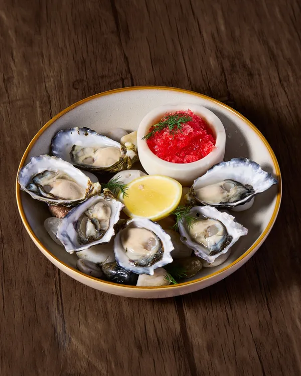 A bowl of freshly shucked oysters with lemon and dressing