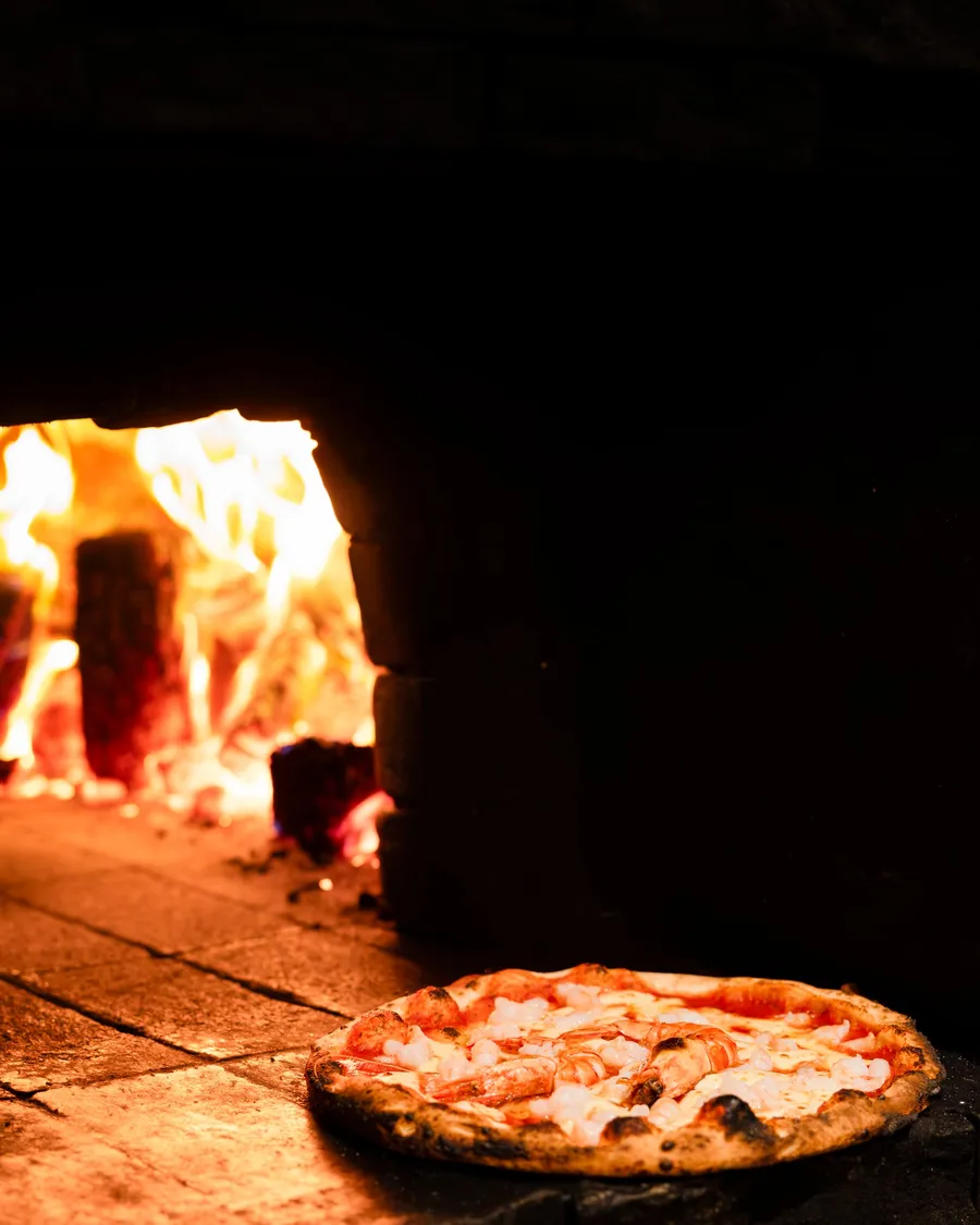 A Margherita at the mouth of the wood-fired oven