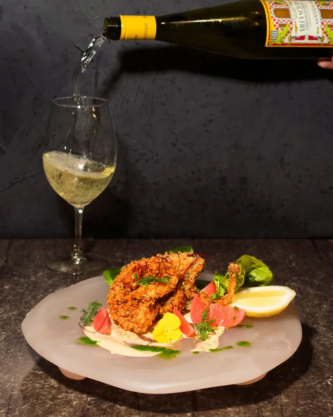 Sardinian Vermentino poured beside a plated seafood dish